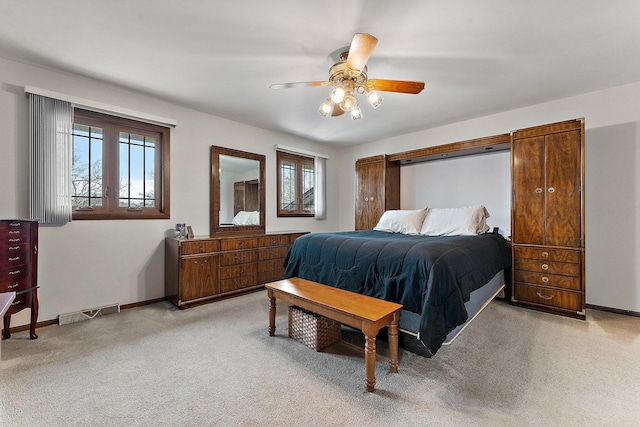 bedroom featuring ceiling fan, multiple windows, and light carpet