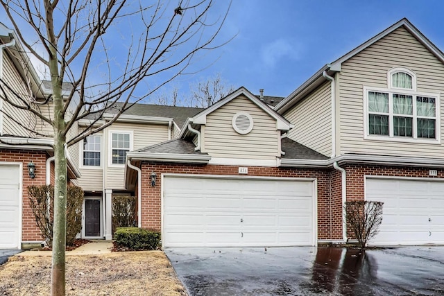 townhome / multi-family property featuring a garage, brick siding, and driveway