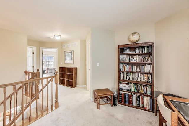 interior space featuring visible vents, an upstairs landing, light colored carpet, and baseboards