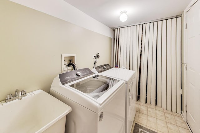 clothes washing area featuring laundry area, light tile patterned floors, washing machine and dryer, and a sink