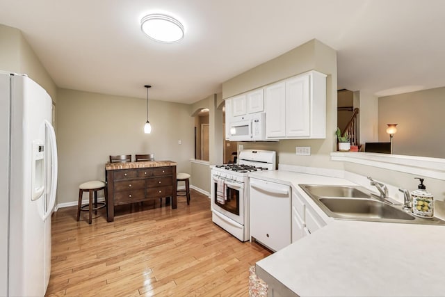 kitchen featuring a sink, white cabinetry, white appliances, light wood-style floors, and arched walkways