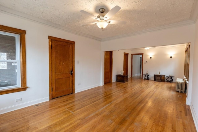 spare room featuring radiator, light wood-type flooring, ceiling fan, crown molding, and a textured ceiling