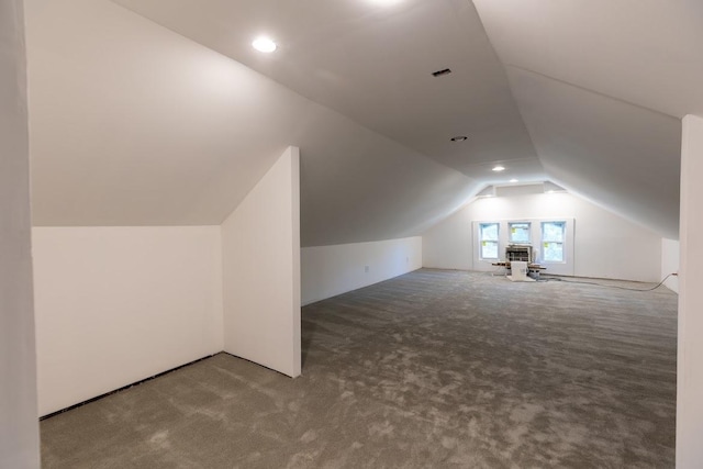 additional living space featuring light colored carpet and lofted ceiling