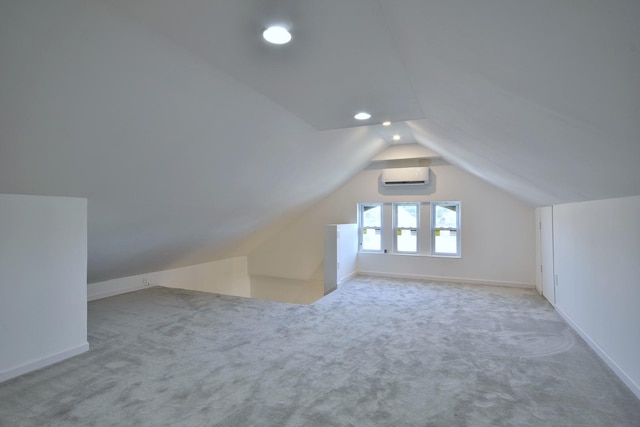 additional living space with vaulted ceiling, light carpet, and an AC wall unit