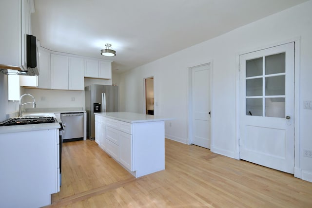 kitchen featuring stainless steel appliances, white cabinetry, a kitchen island, and light hardwood / wood-style flooring