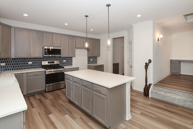 kitchen with gray cabinetry, hanging light fixtures, a center island, and appliances with stainless steel finishes