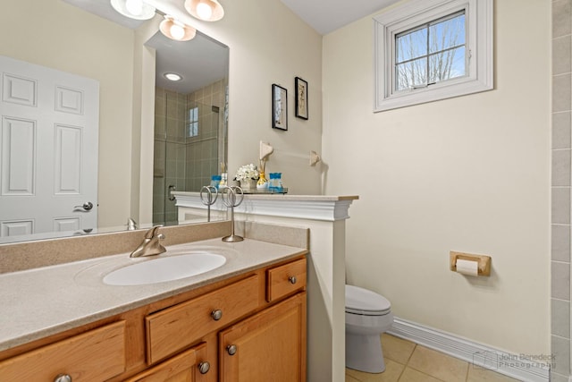 bathroom with baseboards, tiled shower, toilet, tile patterned floors, and vanity