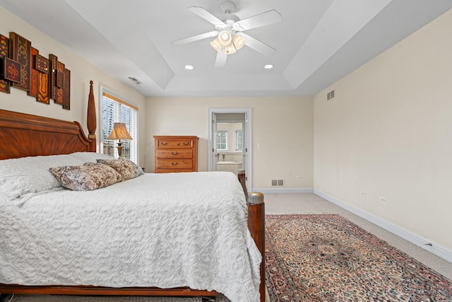 bedroom featuring visible vents, a tray ceiling, light colored carpet, and baseboards