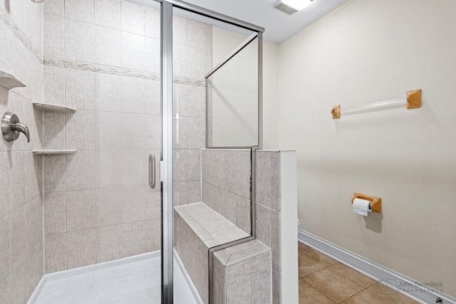 bathroom featuring tile patterned flooring, toilet, visible vents, baseboards, and a stall shower