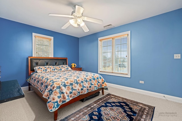 carpeted bedroom featuring a ceiling fan, visible vents, and baseboards