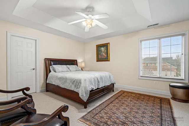 bedroom featuring a ceiling fan, visible vents, baseboards, carpet, and a raised ceiling