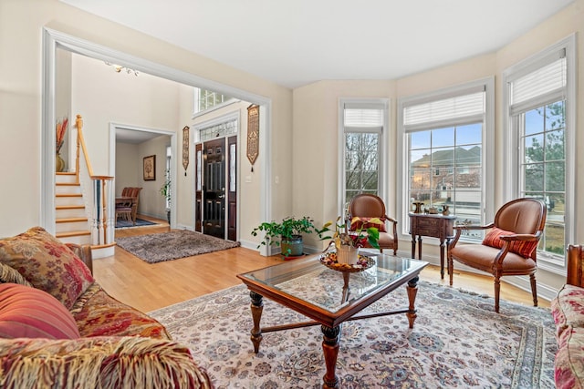 living area featuring stairs, a wealth of natural light, baseboards, and wood finished floors