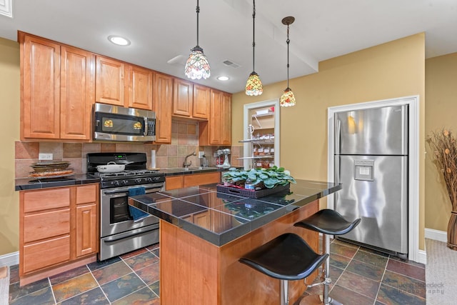 kitchen with stone tile flooring, stainless steel appliances, backsplash, and a kitchen breakfast bar