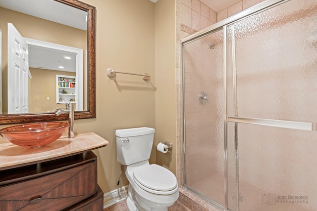 bathroom featuring toilet, a shower stall, baseboards, and vanity