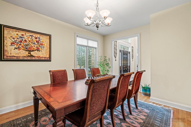 dining area featuring a chandelier, wood finished floors, and baseboards