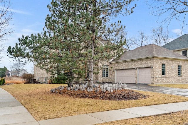 view of front facade with a garage, a shingled roof, brick siding, driveway, and a front lawn