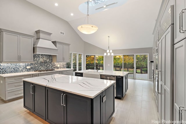 kitchen featuring pendant lighting, gray cabinetry, a center island, light stone counters, and custom range hood