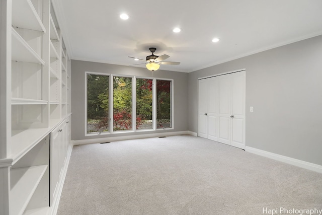 unfurnished bedroom featuring crown molding, light colored carpet, ceiling fan, and a closet