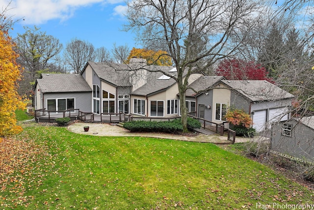 rear view of house featuring a garage, a wooden deck, a sunroom, and a yard