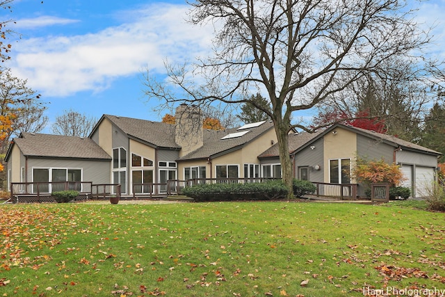 back of property with a lawn, a sunroom, and a deck