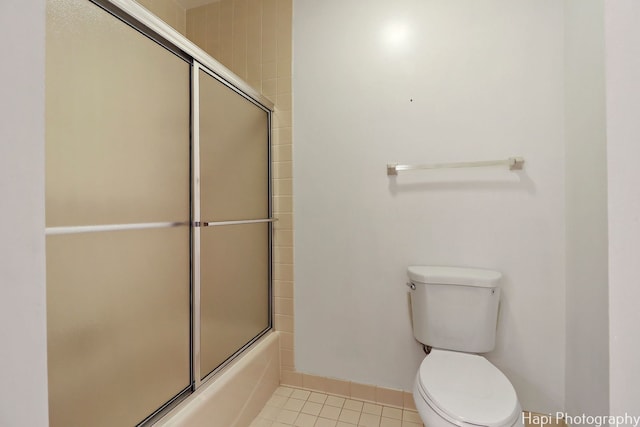 bathroom featuring tile patterned floors, enclosed tub / shower combo, and toilet