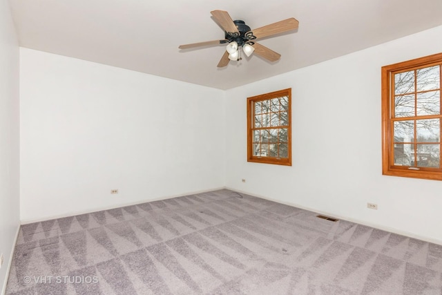 carpeted empty room with visible vents, a ceiling fan, and baseboards