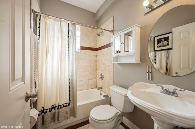 bathroom featuring toilet, shower / tub combo with curtain, and a sink