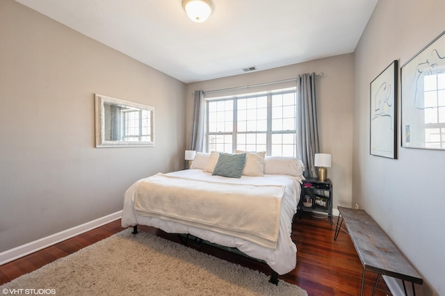 bedroom with wood finished floors, visible vents, and baseboards