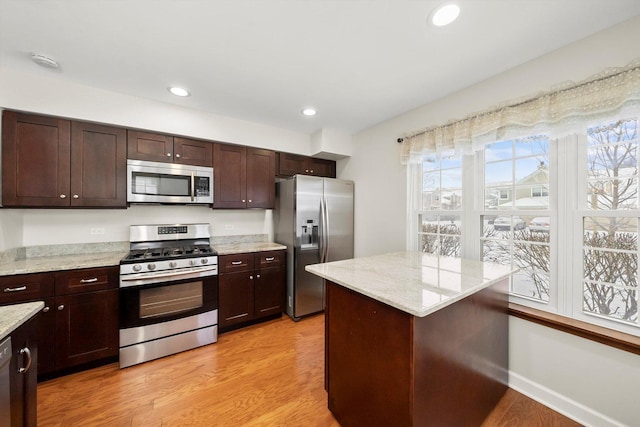 kitchen featuring light stone countertops, dark brown cabinets, stainless steel appliances, and light hardwood / wood-style floors