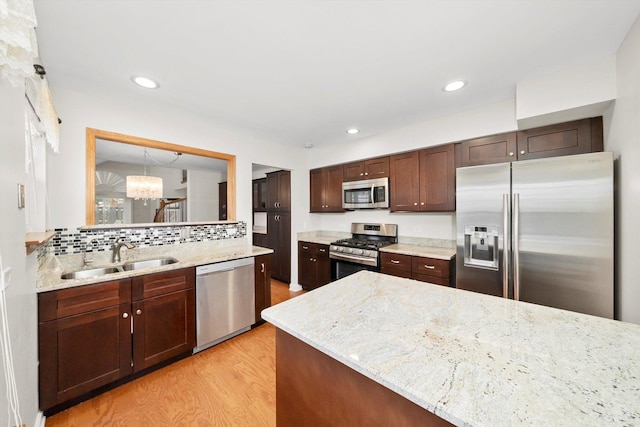 kitchen with appliances with stainless steel finishes, sink, backsplash, dark brown cabinetry, and light hardwood / wood-style flooring