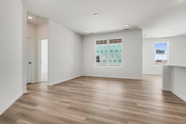 unfurnished room with light wood-type flooring, a healthy amount of sunlight, and baseboards