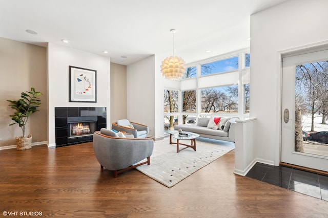 living room with a tile fireplace, dark wood-style flooring, a healthy amount of sunlight, and baseboards