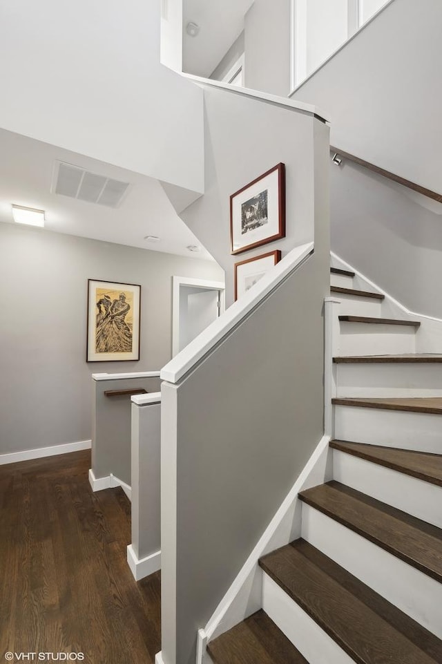 staircase featuring wood finished floors, visible vents, and baseboards