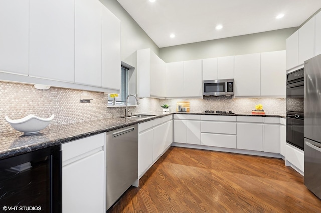 kitchen featuring appliances with stainless steel finishes, beverage cooler, a sink, and backsplash