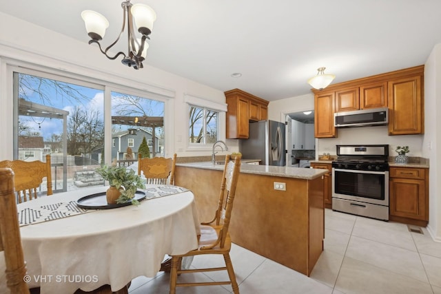 kitchen featuring a kitchen island, hanging light fixtures, light tile patterned floors, stainless steel appliances, and an inviting chandelier