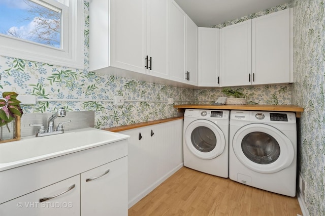 laundry area with cabinets, light wood-type flooring, sink, and independent washer and dryer