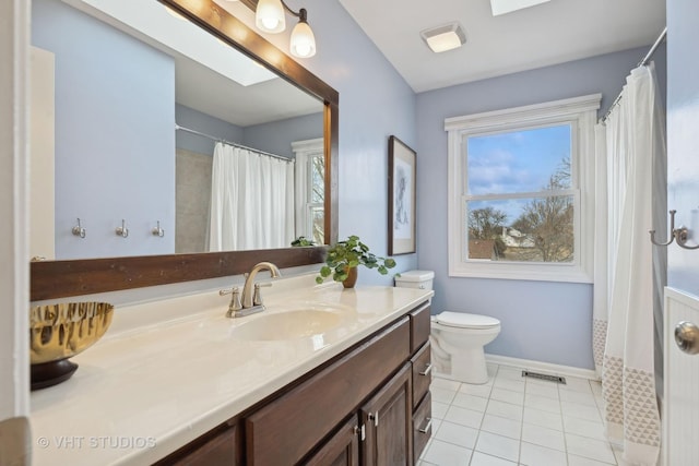 bathroom with tile patterned flooring, vanity, a skylight, and a healthy amount of sunlight