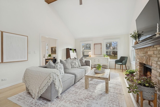 living room featuring high vaulted ceiling, a fireplace, and light hardwood / wood-style floors