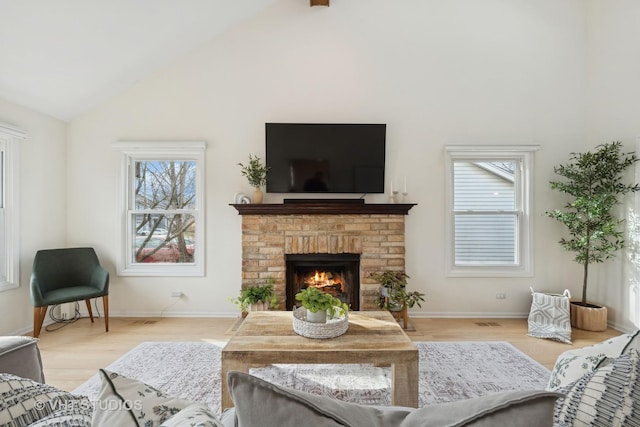 living room featuring a fireplace, high vaulted ceiling, and light hardwood / wood-style flooring