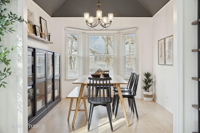 dining space with lofted ceiling, an inviting chandelier, and light wood-type flooring