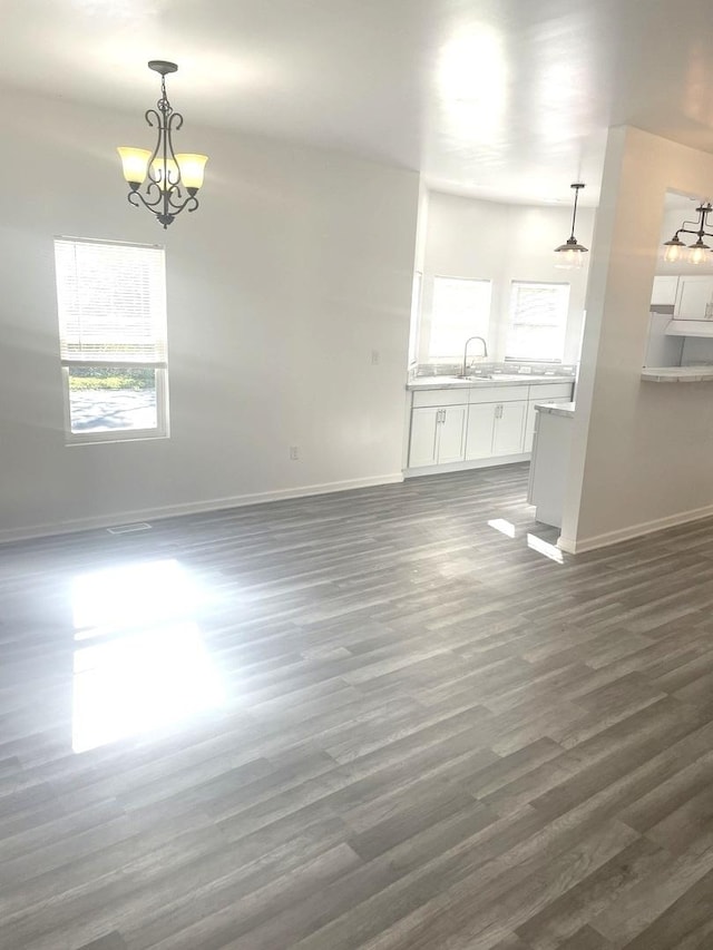 unfurnished living room with an inviting chandelier, dark hardwood / wood-style flooring, and sink