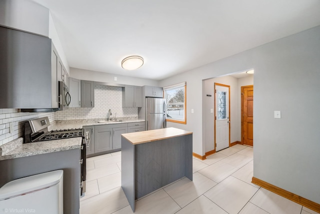 kitchen with tasteful backsplash, appliances with stainless steel finishes, sink, and gray cabinetry