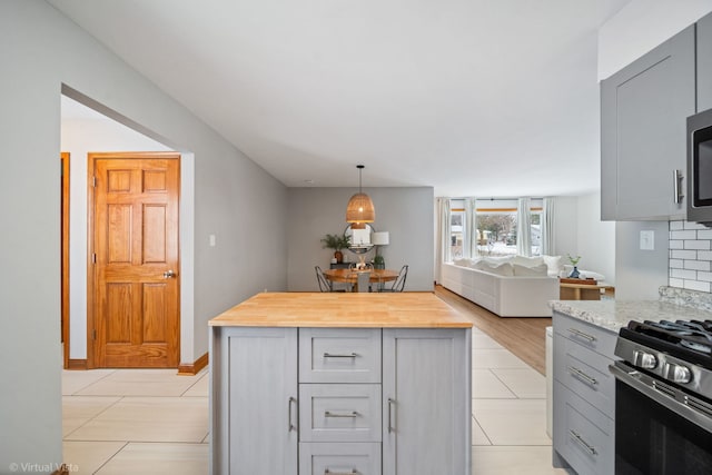 kitchen featuring gray cabinets, appliances with stainless steel finishes, wooden counters, backsplash, and hanging light fixtures