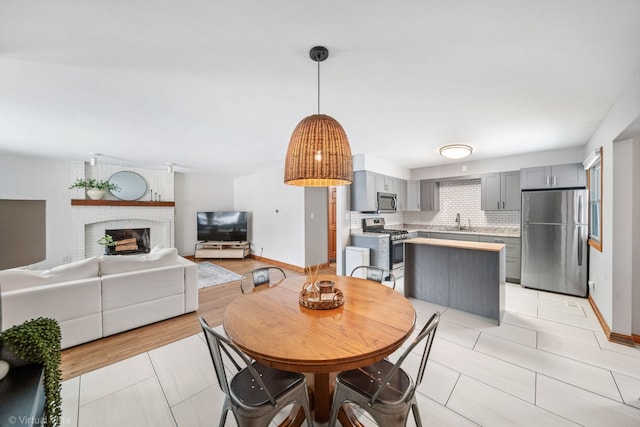 dining room with a brick fireplace, sink, and light tile patterned floors