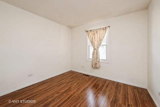 empty room featuring visible vents, baseboards, and wood finished floors