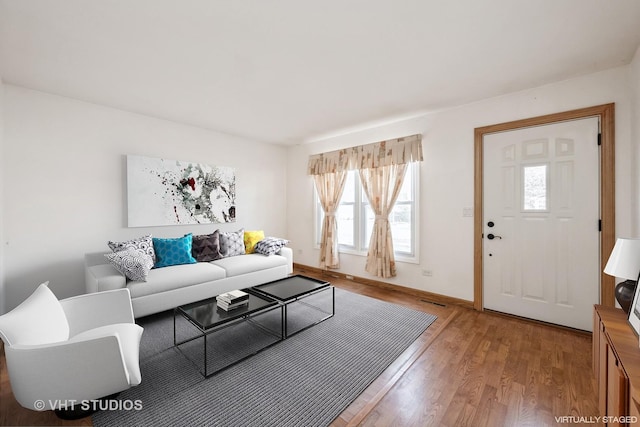 living room with visible vents, light wood-style flooring, and baseboards