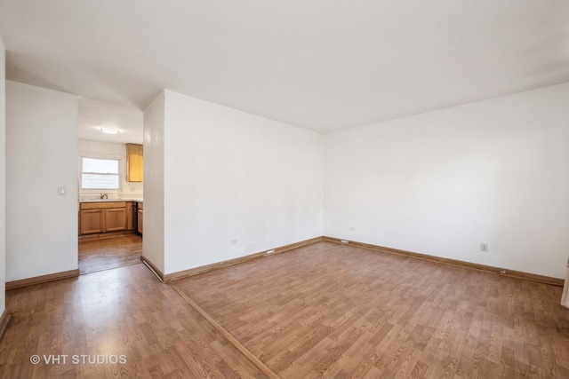 unfurnished room with a sink, baseboards, and light wood finished floors