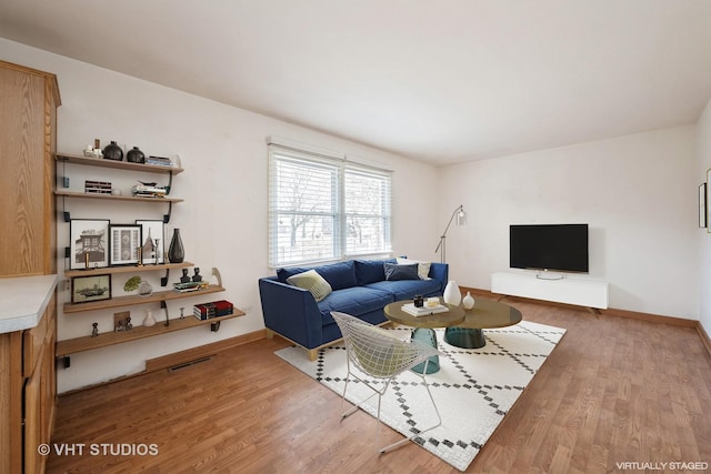 living room featuring visible vents, baseboards, and wood finished floors