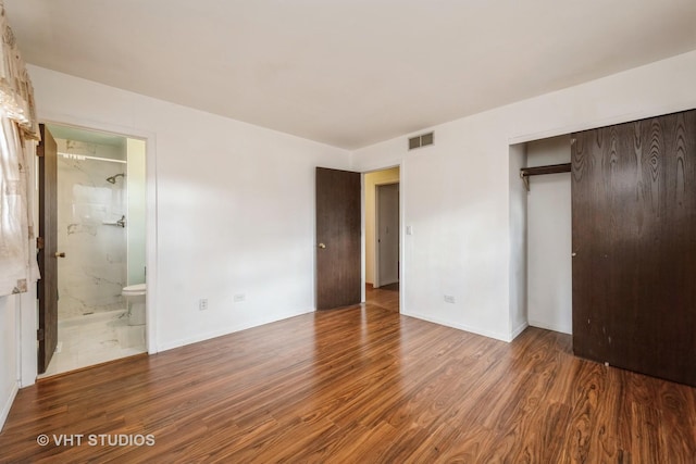 unfurnished bedroom featuring visible vents, baseboards, a closet, and wood finished floors