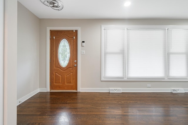 foyer entrance with dark wood-type flooring, visible vents, and baseboards